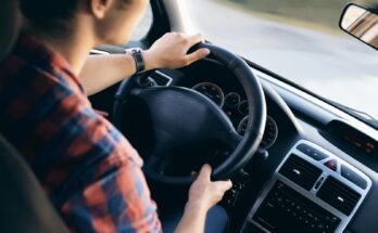 Close-up view of a man driving a modern car, showing dashboard and steering details.