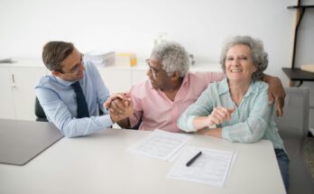 Senior couple in office meeting with consultant, discussing financial documents and smiling.
